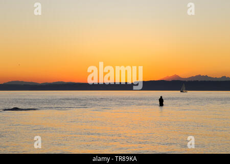 La pêche est un pêcheur Golden Gardens Park, Seattle, Washington au cours d'un magnifique coucher de soleil Banque D'Images