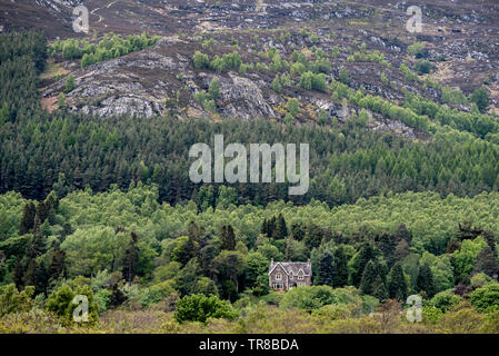 La vue à partir de la Caserne Ruthven vers une maison solitaire au pied de Creag Bheag près de Kingussie dans le parc national de Cairngorm, Ecosse, Royaume-Uni. Banque D'Images