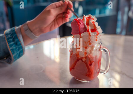 Fraise Testy icecream. Mug cristal avec delicios icecream et garniture aux fraises. Woman eating icecream. Banque D'Images