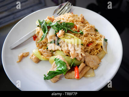 Nouilles instantanées poulet sauté piment et feuille de basilic sur plaque blanche vue de dessus - le style Thai Noodle alimentaire Banque D'Images