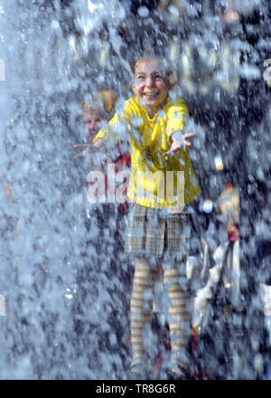 Happy girl à la fontaine de jouer avec de l'eau Banque D'Images