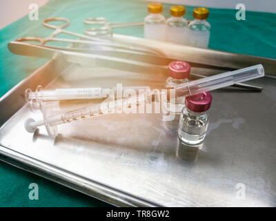 Instruments médicaux matériel / seringue aiguille d'injection de drogues médicales dans le bac en acier chirurgical pour l'infirmière ou du médecin sur le tableau en tissu vert Banque D'Images