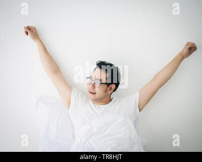 Happy Asian man stretching sur lit après service, style de concept. Banque D'Images