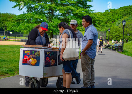 Les promeneurs du parc s'est arrêté par la glace fruits panier pour en obtenir un. Banque D'Images