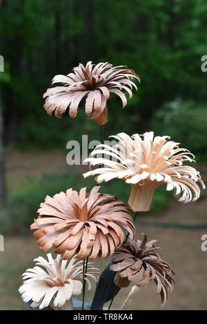 Vue rapprochée d'un groupe de bois sculpté fleurs de diverses couleurs avec une forêt en arrière-plan Banque D'Images
