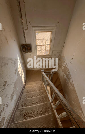 Vue depuis un escalier dans un bâtiment abandonné dans le bain désert de Namibie. Banque D'Images