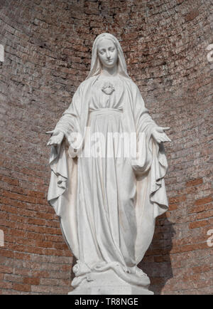 Statue en pierre de la Vierge Marie. Sur l'arrière-plan, mur de brique rouge. Idéal pour Noël et Pâques et d'autres concepts. Banque D'Images