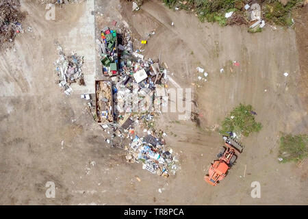 Tracteur Orange travaillant dans un centre de recyclage et de tri des déchets, des séquences aériennes. Banque D'Images