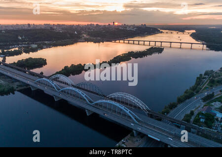 Coucher du Soleil vue aérienne sur un pont Darnitsky, gros véhicule et transport ferroviaire voie à Kiev, Ukraine Banque D'Images