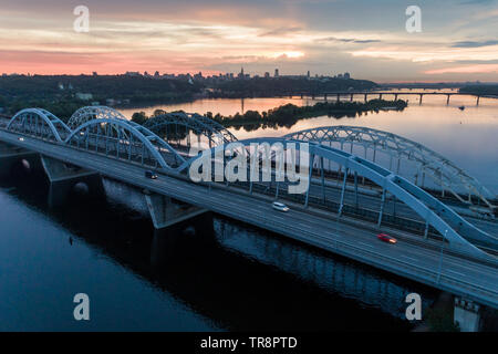 Coucher du Soleil vue aérienne sur un pont Darnitsky, gros véhicule et transport ferroviaire voie à Kiev, Ukraine Banque D'Images