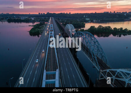 Coucher du Soleil vue aérienne sur un pont Darnitsky, gros véhicule et transport ferroviaire voie à Kiev, Ukraine Banque D'Images