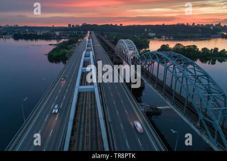 Coucher du Soleil vue aérienne sur un pont Darnitsky, gros véhicule et transport ferroviaire voie à Kiev, Ukraine Banque D'Images