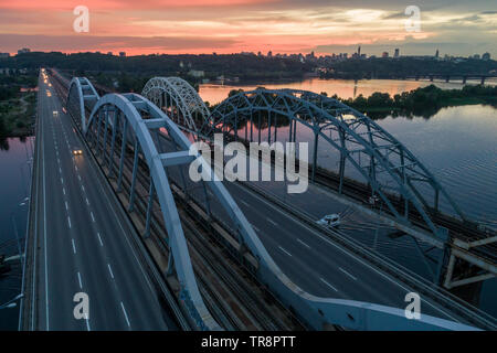 Coucher du Soleil vue aérienne sur un pont Darnitsky, gros véhicule et transport ferroviaire voie à Kiev, Ukraine Banque D'Images