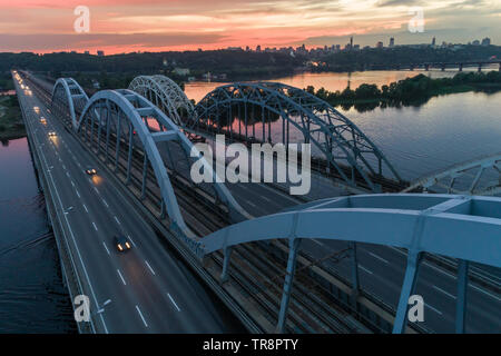 Coucher du Soleil vue aérienne sur un pont Darnitsky, gros véhicule et transport ferroviaire voie à Kiev, Ukraine Banque D'Images