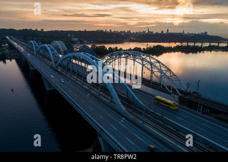 Coucher du Soleil vue aérienne sur un pont Darnitsky, gros véhicule et transport ferroviaire voie à Kiev, Ukraine Banque D'Images