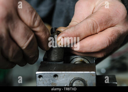 La réparation d'un injecteur mécanique diesel. Mans mains démonter une pincé de l'injecteur dans un étau. Banque D'Images