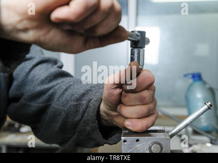 La réparation d'un injecteur mécanique diesel. La main de l'homme tenant une clé dynamométrique et untwists détails coincé dans un étau. Banque D'Images