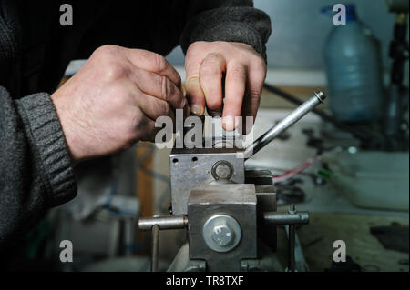 La réparation d'un injecteur mécanique diesel. Mans mains démonter une pincé de l'injecteur dans un étau. Banque D'Images