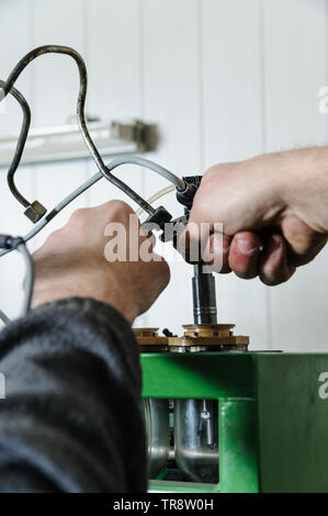 Mécanique a réparation d'un injecteur de gazole. Les mains de l'utilisateur installent l'injecteur sur une machine de banc d'essai. Un homme vérifie le travail d'une buse. Banque D'Images