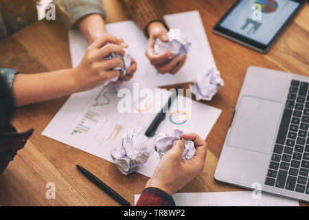 Un homme d'affaires documents bousillé à la main avec ordinateur portable, tablette et du papier sur la table de travail à une réunion Banque D'Images