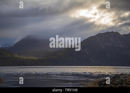 La lumière du matin et de l'humeur par le Romsdalsfjorden, la Norvège. Les rayons du soleil percent les nuages, tôt le matin, lumière chaude. Banque D'Images