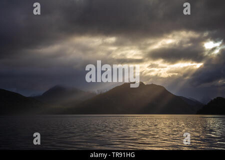 La lumière du matin et de l'humeur par le Romsdalsfjorden, la Norvège. Les rayons du soleil percent les nuages, tôt le matin, lumière chaude. Banque D'Images