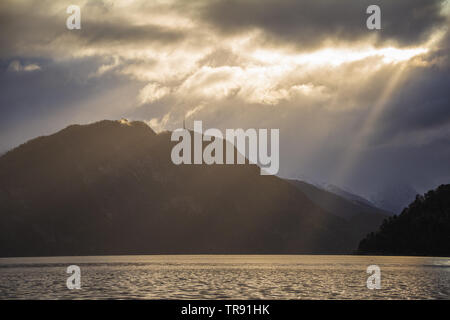 La lumière du matin et de l'humeur par le Romsdalsfjorden, la Norvège. Les rayons du soleil percent les nuages, tôt le matin, lumière chaude. Banque D'Images