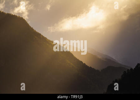 La lumière du matin et de l'humeur par le Romsdalsfjorden, la Norvège. Les rayons du soleil percent les nuages, tôt le matin, lumière chaude. Banque D'Images