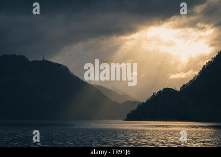 La lumière du matin et de l'humeur par le Romsdalsfjorden, la Norvège. Les rayons du soleil percent les nuages, tôt le matin, lumière chaude. Banque D'Images