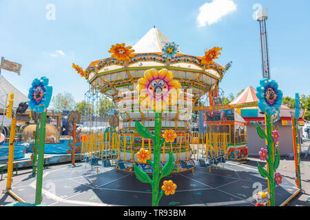 Bergame, Italie - Mai 2019 : les chaînes de carrousel pour les enfants dans des couleurs vives pendant un procès équitable dans un parc Italien lampes en forme de fleurs. Printemps, belle journée Banque D'Images