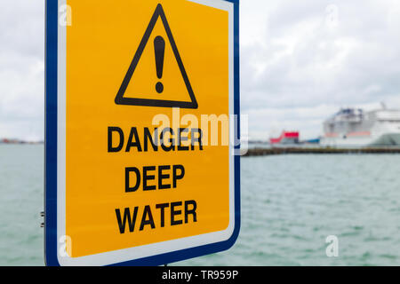 Danger l'eau profonde. Panneau d'avertissement jaune monté dans le port de Southampton Banque D'Images