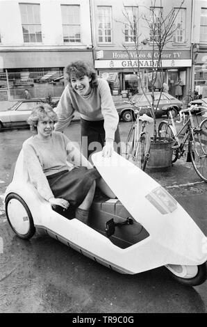 L'Angleterre. 10 janvier 1985. Le lancement de la Sinclair C5, véhicule électrique ou velomobile, conçu par Sir Clive Sinclair. Les membres du public se rassembler autour du véhicule pour donner leur avis. Une jeune femme est assise dans le véhicule pendant que l'autre jeune femme regarde. Banque D'Images