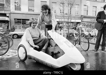 L'Angleterre. 10 janvier 1985. Le lancement de la Sinclair C5, véhicule électrique ou velomobile, conçu par Sir Clive Sinclair. Une jeune femme est assise dans le véhicule pendant que l'autre jeune femme regarde. Banque D'Images