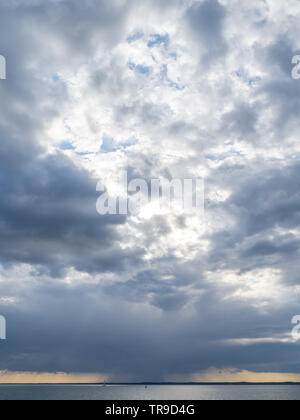 Un rainfront déménagement approchant sur Solent avec yacht unique solitaire en mer avec bouée sous big sky storm clouds coucher du soleil orange Banque D'Images