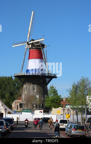 Vue vers le bas rue animée de Leiden, Pays-Bas De Molen De Valk, un moulin à vent historique décorée de drapeau néerlandais pour les célébrations de la fête du Roi en 2019. Banque D'Images