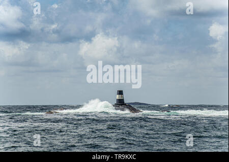 Une marque de navigation noir et blanc sur un petit récif. Banque D'Images