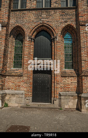 Barrière en bois et fenêtres sur l'église gothique sous une journée ensoleillée, dans une ruelle de Bruges. Charmante ville avec des canaux et de vieux bâtiments en Belgique. Banque D'Images