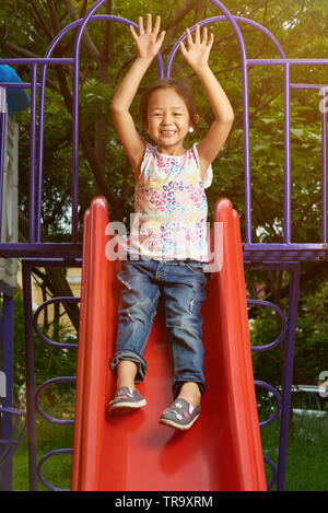 Asian girl ne glisse dans le parc aux beaux jours lumineux Banque D'Images