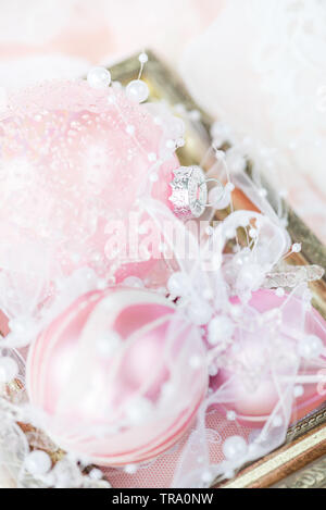 Belle décoration de Noël : boules de Noël rose avec ruban blanc et perles dans un cadre vintage doré sur un fond clair, vertical image Banque D'Images