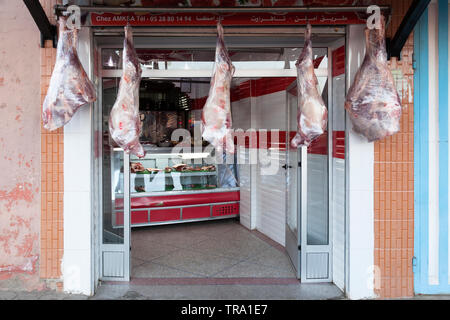 Une boucherie avec de gros morceaux de viande enveloppée dans du plastique et pendants devant le magasin. Tafraoute, Tiznit, Maroc, Province Souss-Massa. Banque D'Images