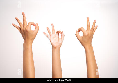 Les femmes part OK sign gesticulant sur fond blanc dans trois Banque D'Images