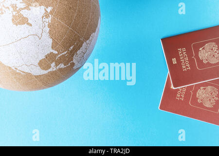Globe de la terre modèle cork et deux passeports sur fond bleu vue du haut. Concept se déplaçant à l'étranger. L'espace de copie, modèle. Banque D'Images