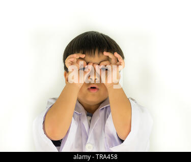 Portrait d'un drôle de petit garçon à la caméra à l'intermédiaire de doigts isolé sur fond blanc Banque D'Images