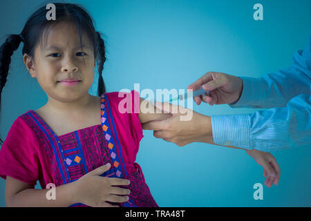 Médecin vaccinant asian cute little girl, isolé sur fond bleu Banque D'Images