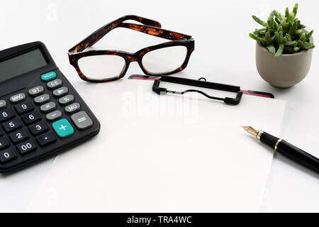Business objects, presse-papiers avec une feuille blanche de papier, stylo, lunettes et calculatrice sur fond blanc Banque D'Images