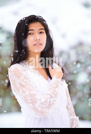 Belle fille de l'adolescence biracial en robe de dentelle blanche standing outdoors in winter Banque D'Images