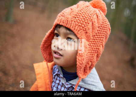 Adorable petit garçon asiatique avec de grands yeux marron portant un wooley hat dans un parc en automne Banque D'Images