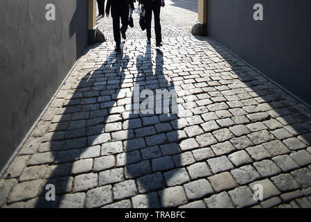 Deux fonctionnaires en costumes noirs marcher ensemble pour travailler dans de longues ombres tôt le matin Banque D'Images