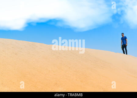 Le jeune homme dans des vêtements décontractés qui marchait vers l'avant dans le désert Banque D'Images