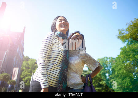 Portrait de deux meilleures amies asiatiques serrant l'autre et souriant dans le soleil d'été Banque D'Images
